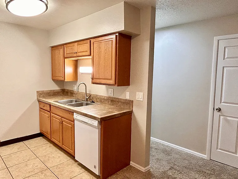 Inviting kitchen featuring warm wooden cabinets, modern fixtures, and a sleek dual sink with a bright atmosphere.