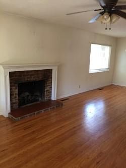 Living room area with hardwood floors and ceiling fan. Fireplace is for decorative purposes only.