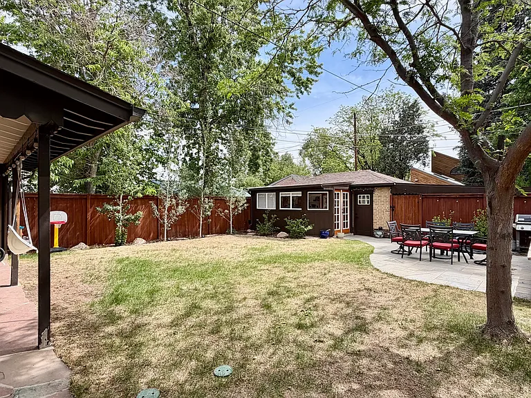 Spacious, fully-fenced backyard complete with a covered patio, uncovered patio, irrigated landscaping and planter box, and numerous trees