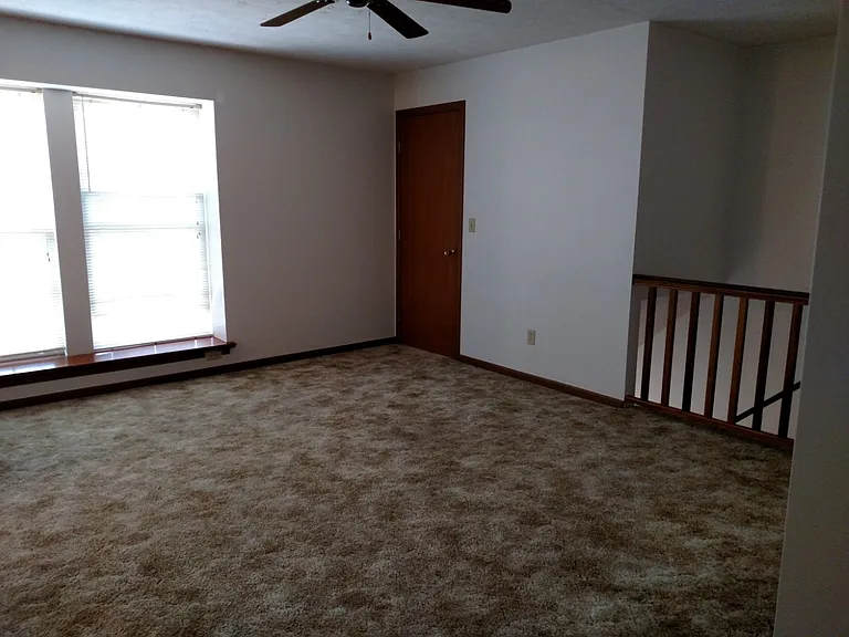 In living room looking at stairwell and front windows.