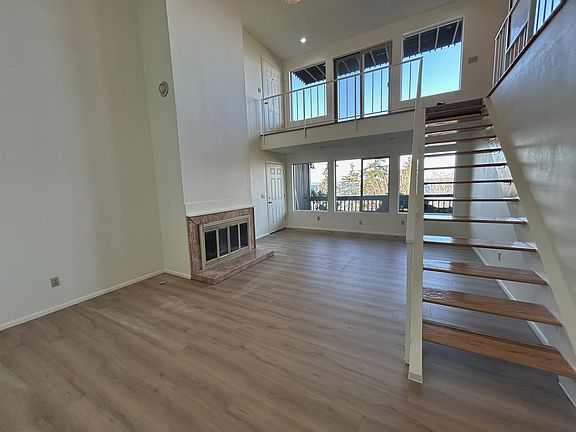 Spacious lower-level living room with expansive ceilings, gas fireplace and natural light.