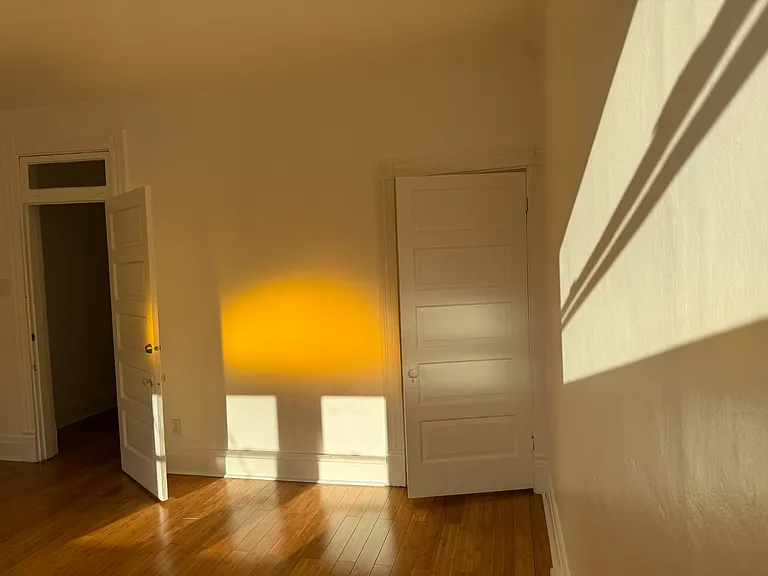 2nd Floor Front Bedroom _ flooded with light, especially beautiful because of the antique stained glass yellow arched transom window, good sized closet and pristine hearth & fireplace