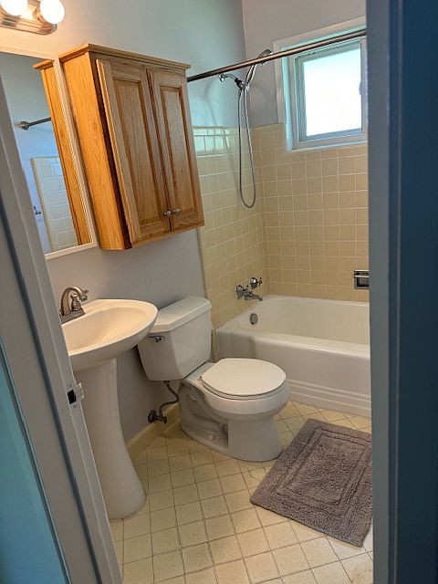 The bathroom features the original 1958 tile and tub with a modern toilet, lighting and pedestal sink.
