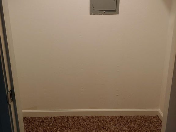 Walk-in bedroom closet. Clothes racks on both sides. Light fixture in ceiling with pull string.