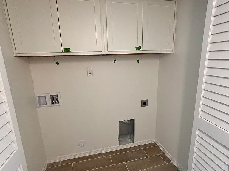 Dedicated laundry room with built-in overhead cabinets for extra storage
