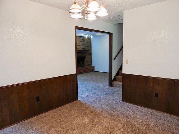 Dining area with view of living area with wood burning fireplace. This carpet has now been replaced with wood flooring.