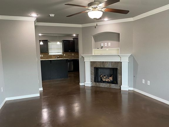 Living room, stained concrete floors, ceiling fan and corner gas log fireplace