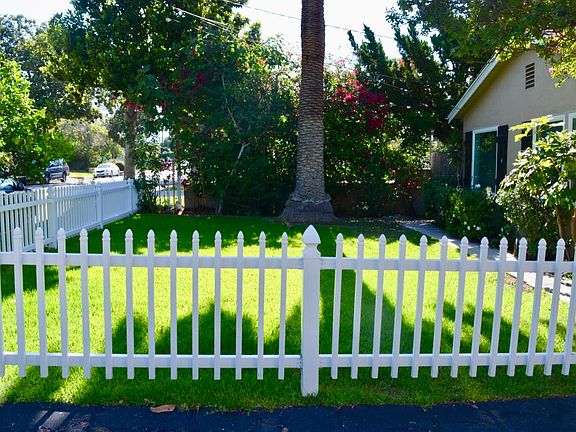 Cute white picket fence encloses the front yard lawn area.