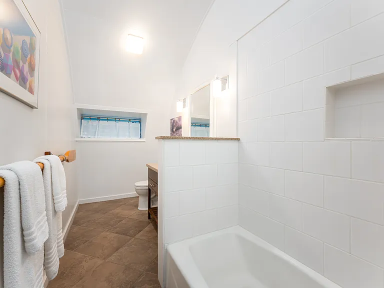 Updated main bathroom featuring a clean tub/shower combo, modern tile finishes, and an extended vanity with ample counter space.