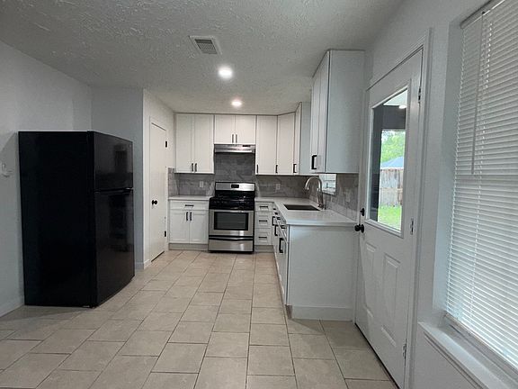 Cocina renovada con electrodomesticos, piso de loseta, gabinetes y despensa. Comedor con acceso al patio.//

Updated kitchen with modern appliances, sleek tile floors, and ample cabinet space with pantry. Dining area with backyard access.