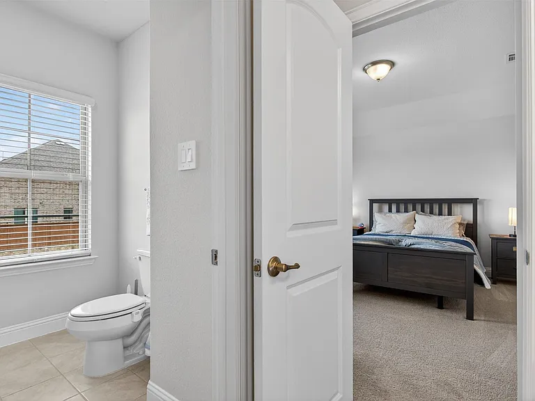 Bright bedroom space with carpet flooring and an overhead flush-mount light fixture