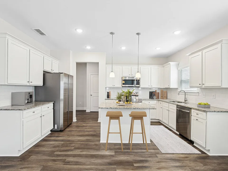View of the kitchen and entry hallway. Offering bar seating, plenty of cabinet space and granite countertops.