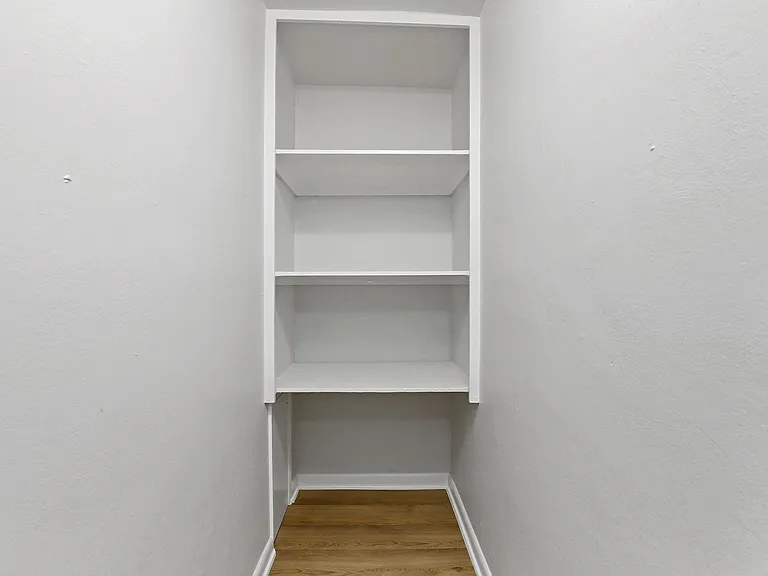 Bright, spacious walk-in closet with minimalist shelving, perfect for organizing your wardrobe and accessories.