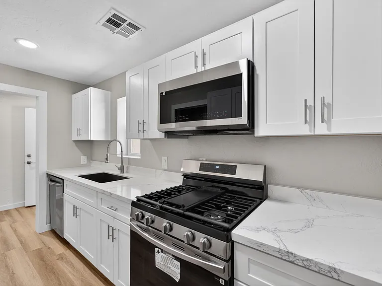 Updated kitchen with quartz-style counters, ample white cabinetry, and stainless steel appliances for everyday cooking.