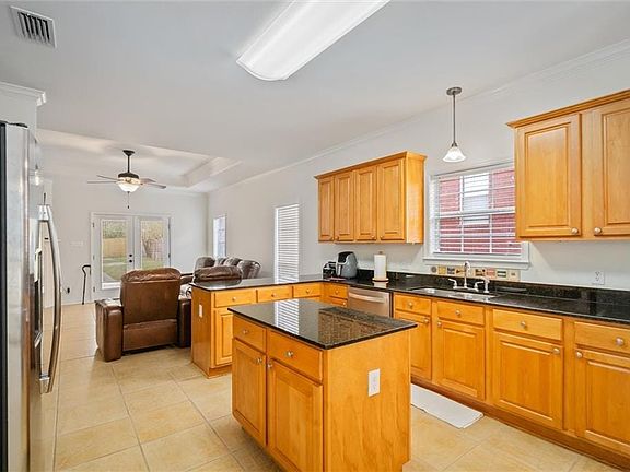 Kitchen with stainless steel appliances, light tile patterned flooring, ornamental molding, a peninsula, and open floor plan