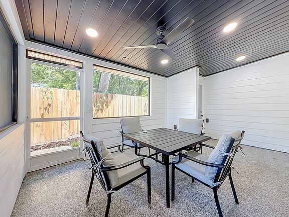 Spacious screened in patio with epoxy floor, wood ceiling fan and a table with four chairs to unwind after a hard day of work, park fun or visiting family.