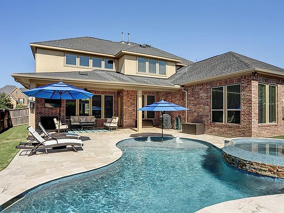 Sparkling pool with sunning ledge, large hot tub & waterfall features. Large covered patio increases your outdoor entertaining options. Homeowners do have a safety gate that will remain with the home.