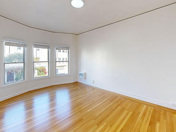 Sunlit room with a large window and wood-like flooring