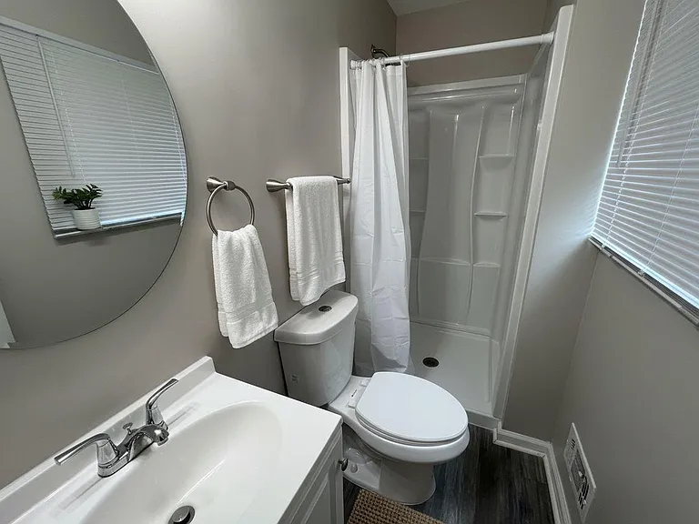 Full bathroom with tub/shower combo, vanity with sink, and a window with blinds for ventilation and natural light.