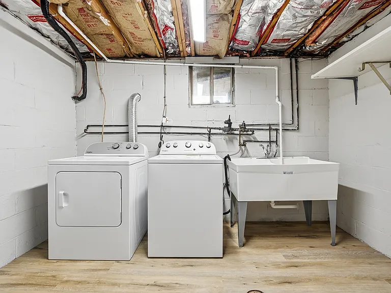 Laundry room equipped with a brand new washer, dryer, and double-bowl laundry tub.