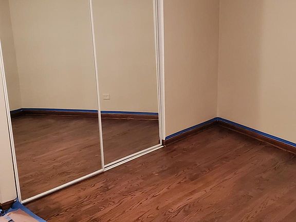 Bedroom with beautifully refurbished hardwood floors. Custom cabinets with mirrored closet doors