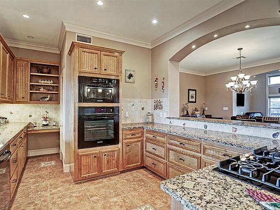 Kitchen has custom beadboard cabinetry, black KitchenAid appliances, granite counters with additional seating at breakfast bar, custom tile backsplash & large pantry.