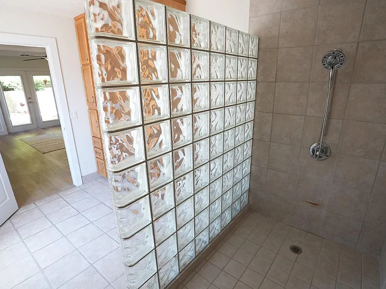 Spacious walk-in shower with tiled surround and a glass-block divider for added privacy and easy maintenance.