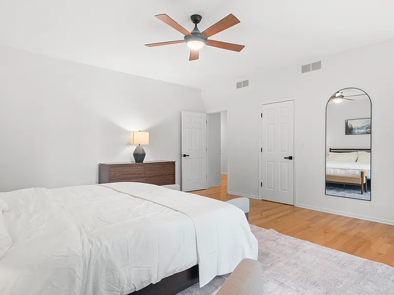 Primary bedroom with a comfortable reading chair, generous closet space, and private ensuite bathroom.