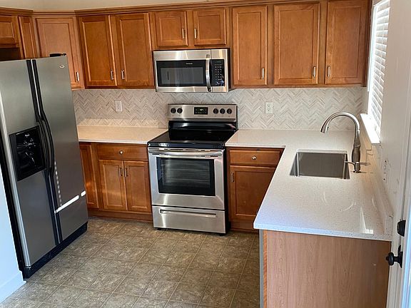 View of kitchen with new: stainless appliances, countertops, backsplash, and sink.