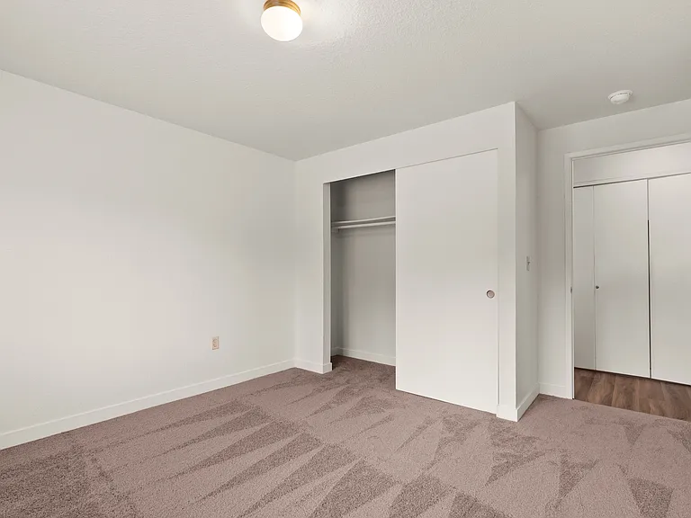 Bright and inviting bedroom with plush carpet, built-in closet, and modern lighting. Bright and inviting bedroom with plush carpet, built-in closet, and modern lighting.
