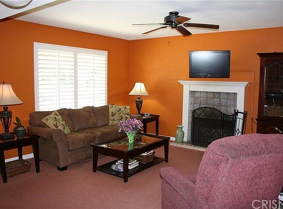 Family/Living Room with upgraded plantation shutters, wood-burning fireplace & ceiling fan.