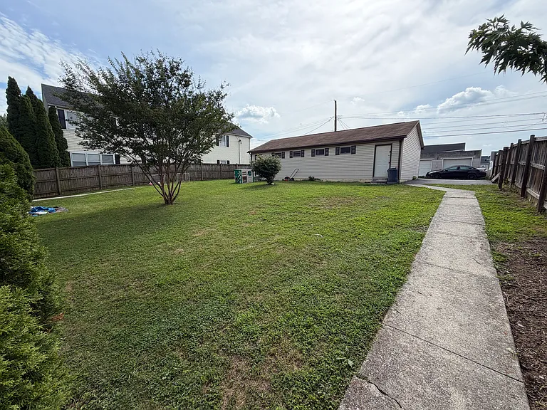 View of back yard from the back of the house. Also shows the garage with off street parking next to it.
