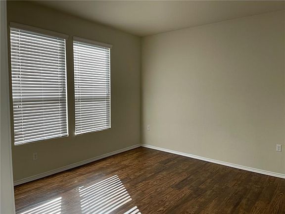 Primary bedroom has laminate wood floors, en-suite bathroom, and walk-in closet. Faces rear of house for privacy