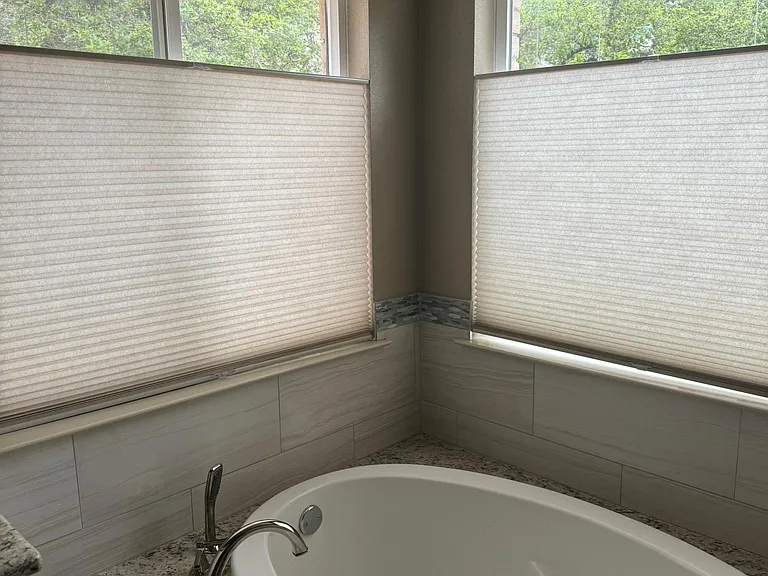 Master bath with soaking tub and view of trees. Shades are top up or down, bottom also up or down down for versatility of view. Also, has a vanity area and two sinks.