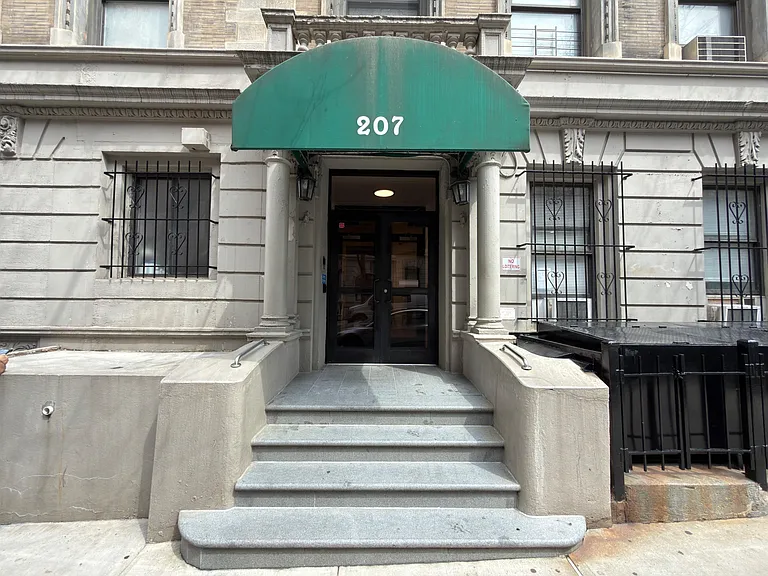 Secure building entry with covered awning, glass double doors, and a short stair approach for easy access.