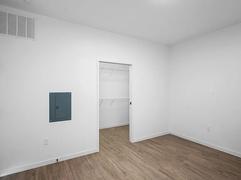 Sleek and modern empty room with stylish wooden flooring, featuring a spacious walk-in closet and clean white walls. Sleek and modern empty room with stylish wooden flooring, featuring a spacious walk-in closet and clean white walls.