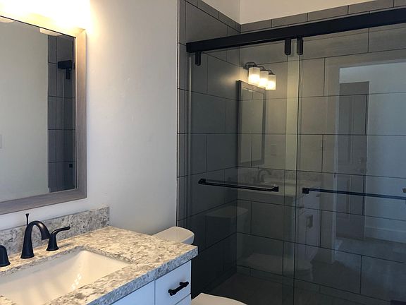 Generous bathroom features quartzite countertops and a large walk-in tiled shower.