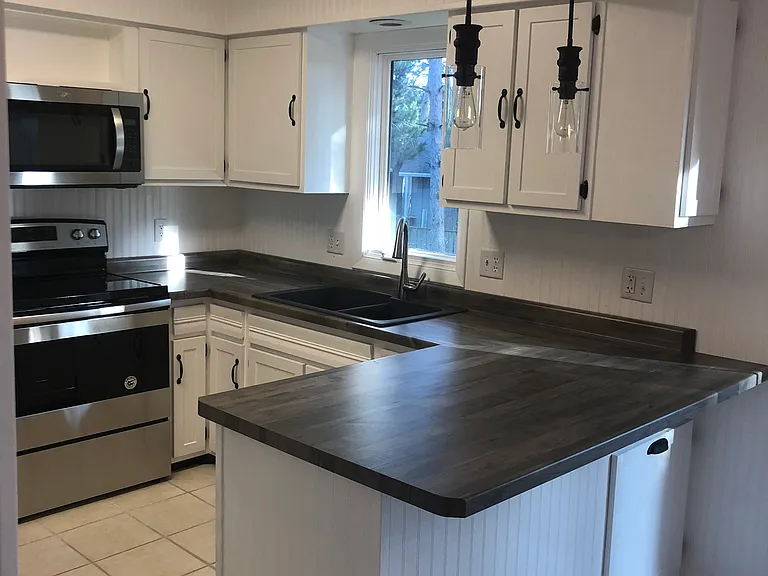 Kitchen showing stove, microwave, window, sink, and counter.