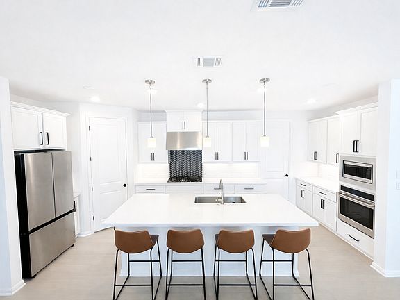 Spacious modern kitchen with large center island, 5-burner gas cooktop with cast-iron grates, and stainless steel appliances including refrigerator, oven, stove, and microwave, perfect for cooking and entertaining.