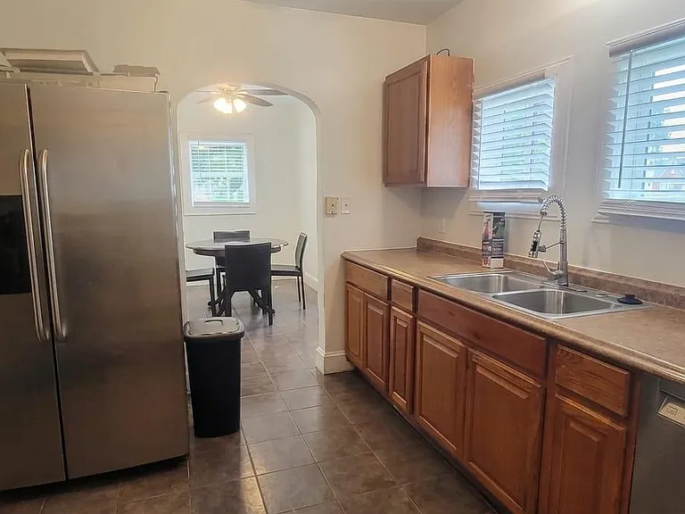 Galley kitchen with stainless steel appliances, ample wood cabinetry, and a double-basin sink with adjacent dining area.