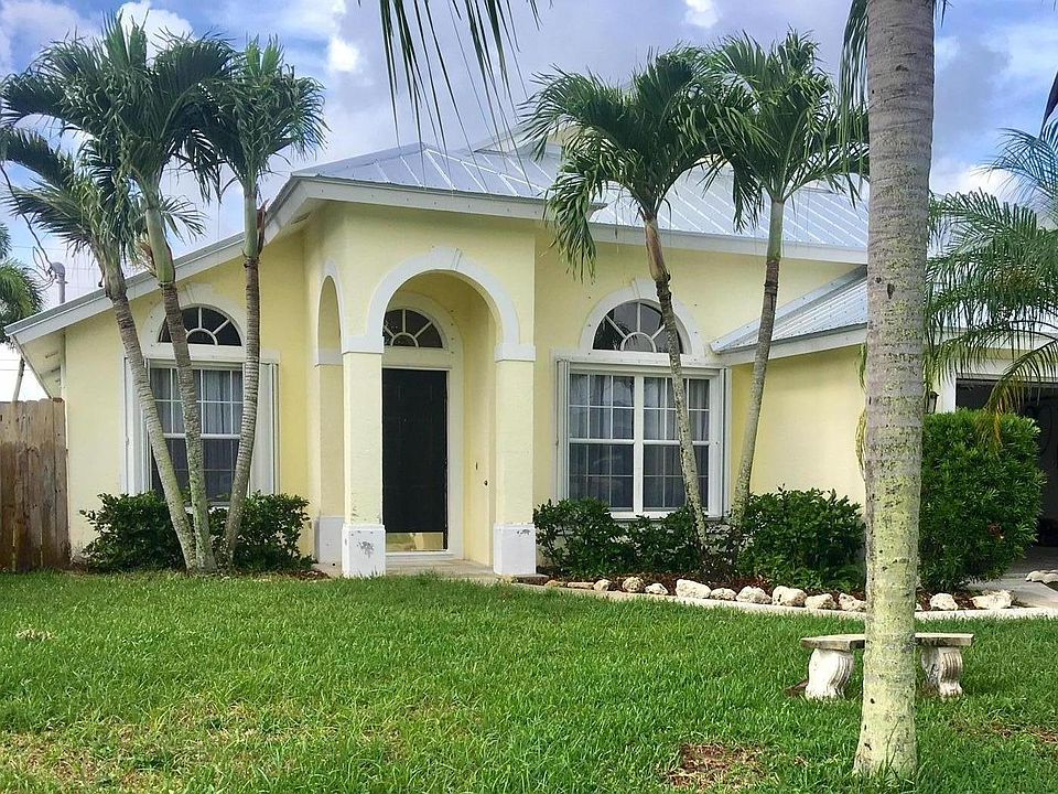 JUPITER HEIGHTS Beautiful yellow concrete built home with new metal hurricane roof and accordian shutters.