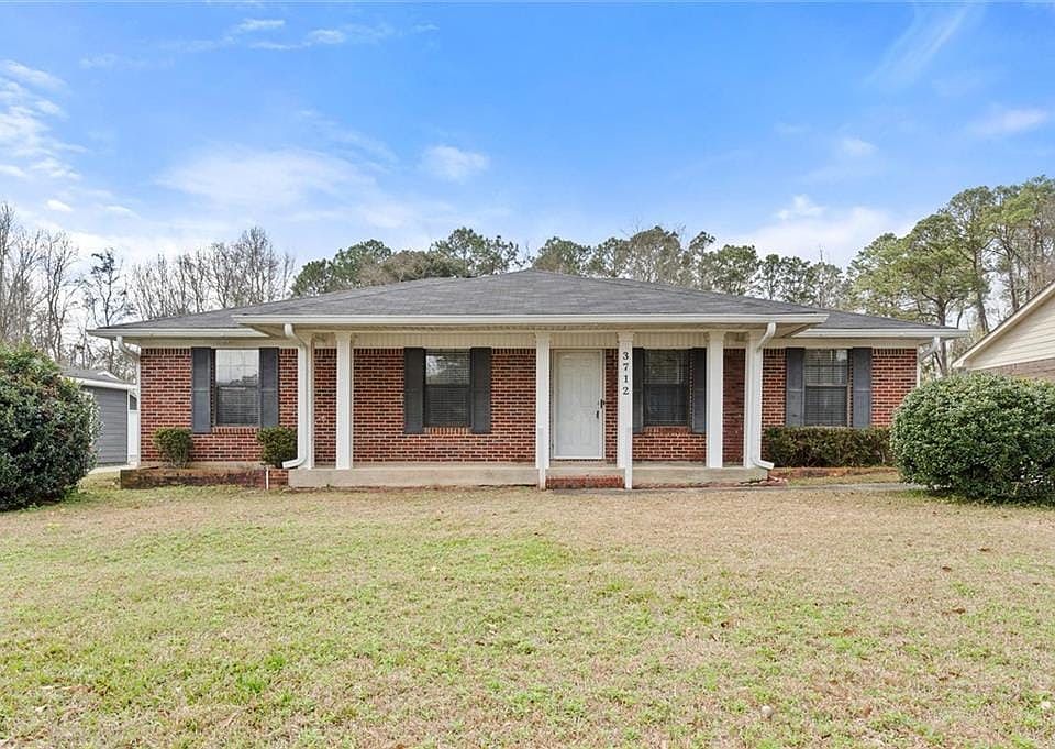 View of front of home featuring a porch, a front yard, brick siding, and roof with shingles