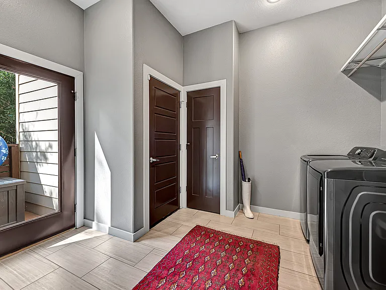 Oversized laundry room with garage and backyard access, pantry, hanging space and sink.
