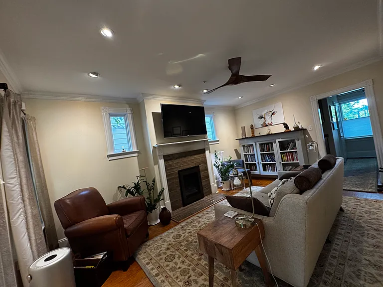Family room w/ gas fireplace. TV on mount that pulls down to eye level. Doorway and hall on right lead to china cabinets, bar, coat closet, and bathroom, and front door.