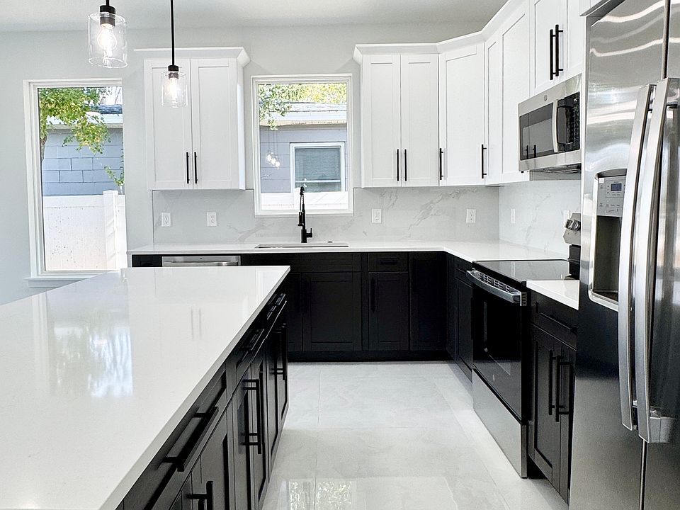 The spacious open kitchen features quartz countertops, stainless steel appliances, soft-close cabinets, a large island, and modern pendant lighting.