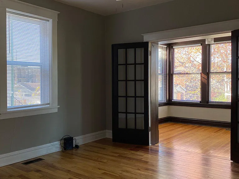 Larger bedroom looking into the sunroom through original French doors.