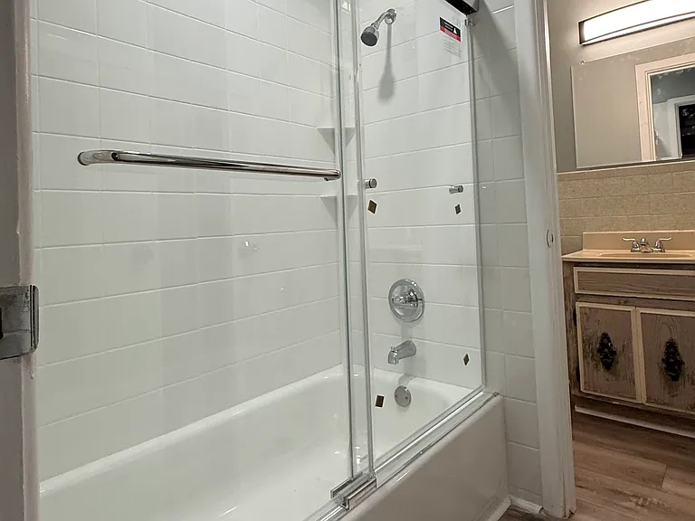 The new bathtub, sliding glass door, faucets, shower head and tile work looking into the master bedroom 1/2 bath.