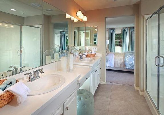 Master bathroom with double sink, a vanity in the middle and a separate toilet room.
