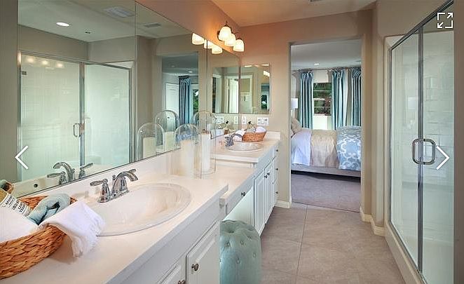 Master bathroom with double sink, a vanity in the middle and a separate toilet room.