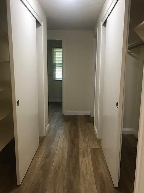 Hallway with shelved closet on one side and utility/coat closet on the other